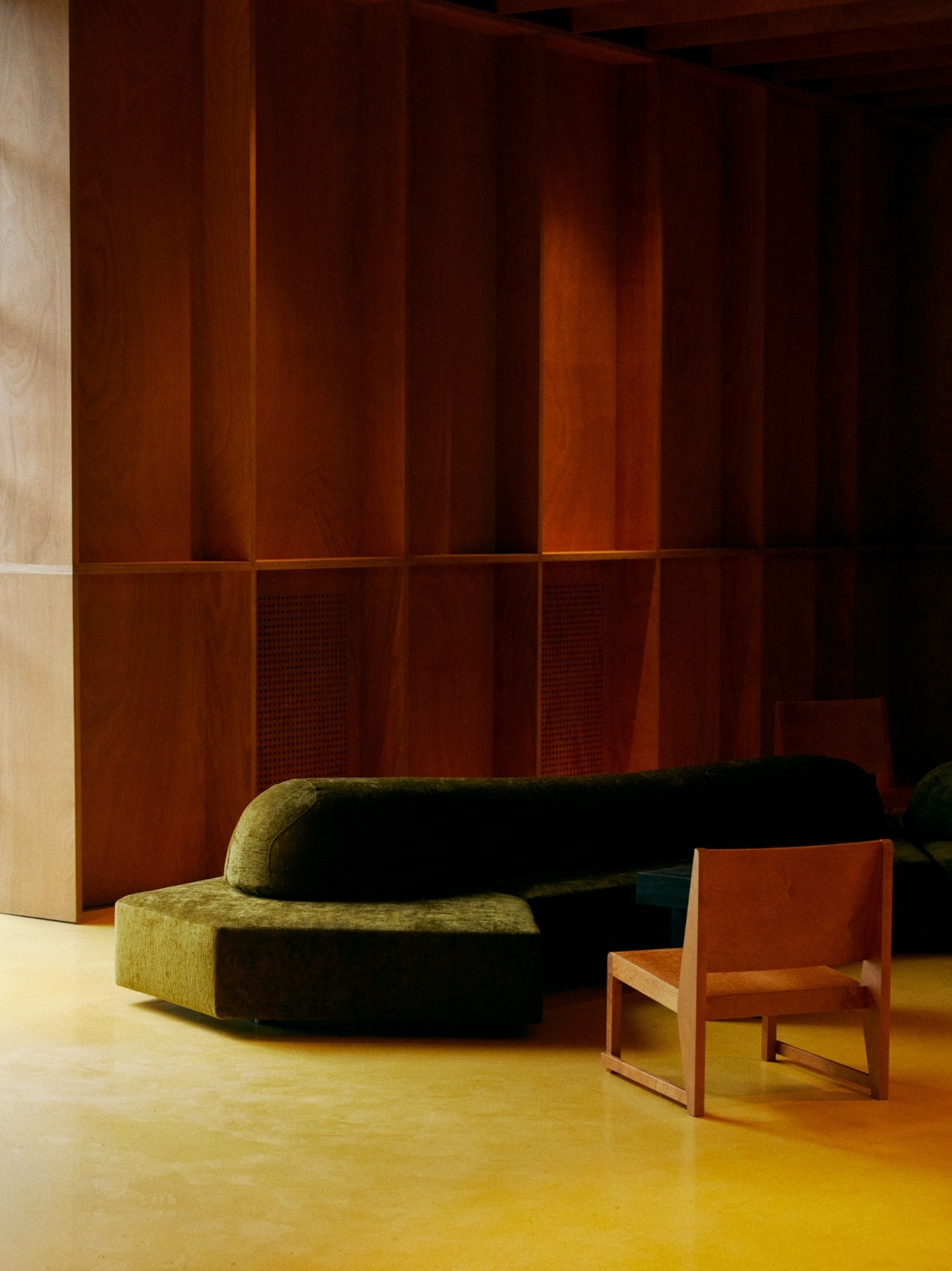 wooden panelling, dark green couch and wooden chair