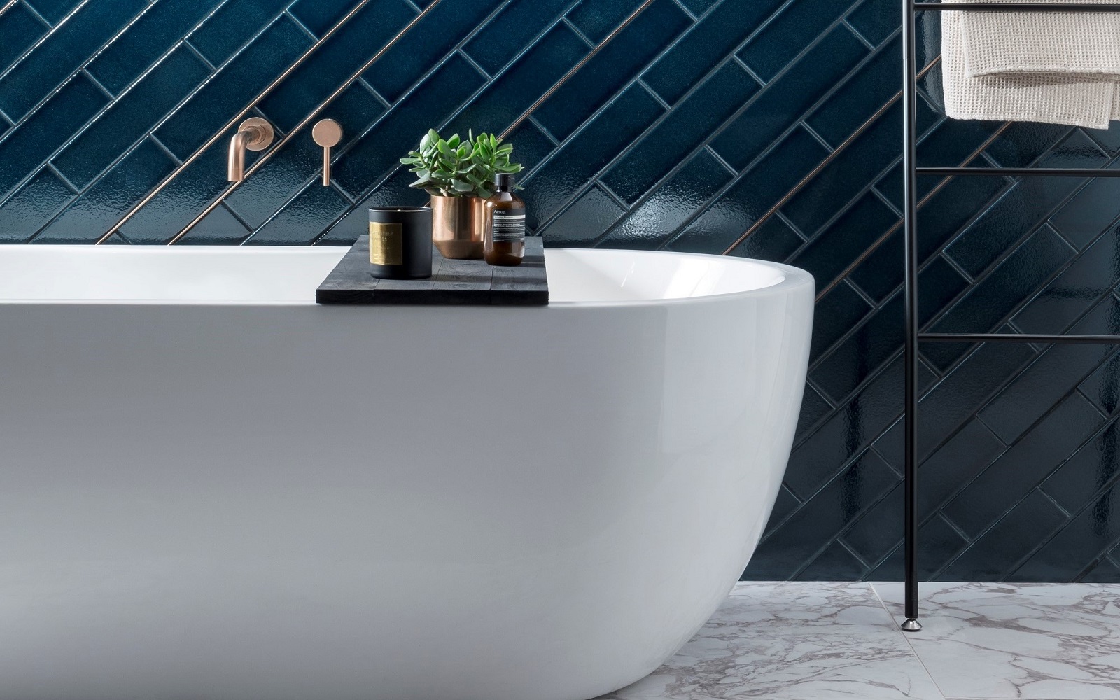 white freestanding bath with blue tiles from Parkside behind and a ladder towel rail alongside