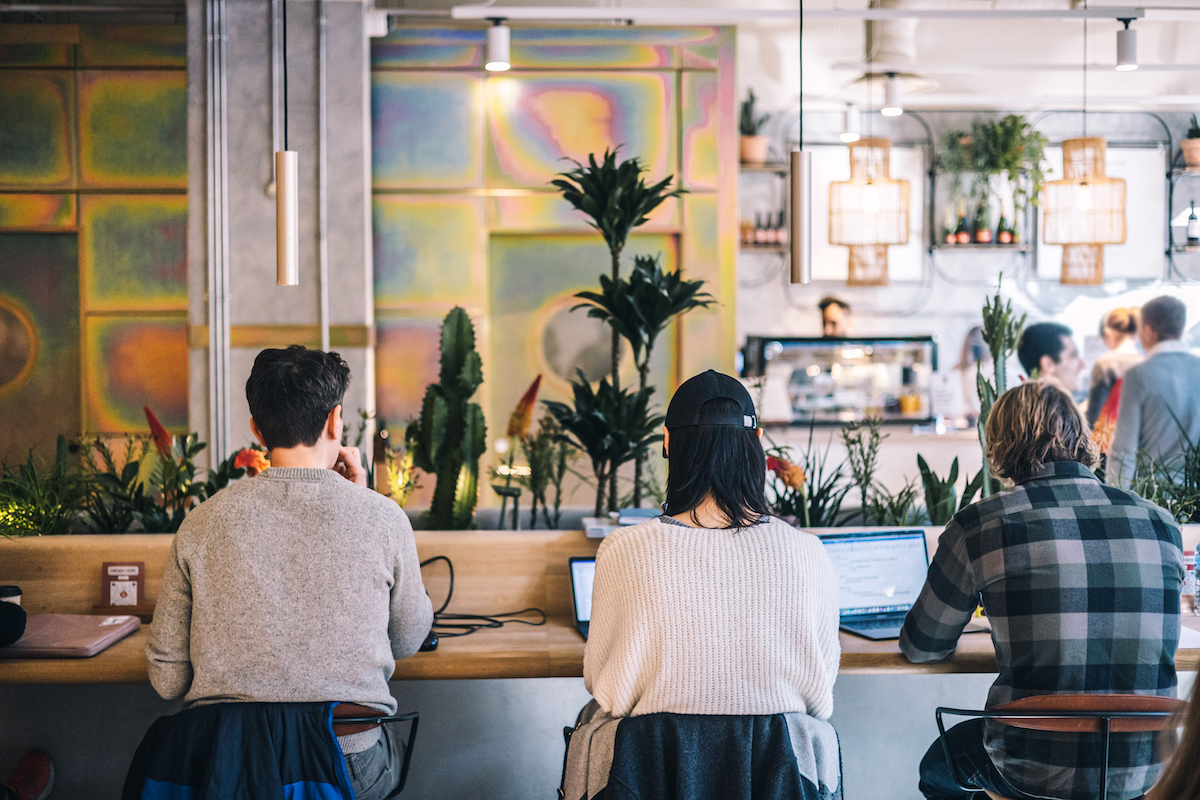 men and woman sitting down working from coffee shop in hotel