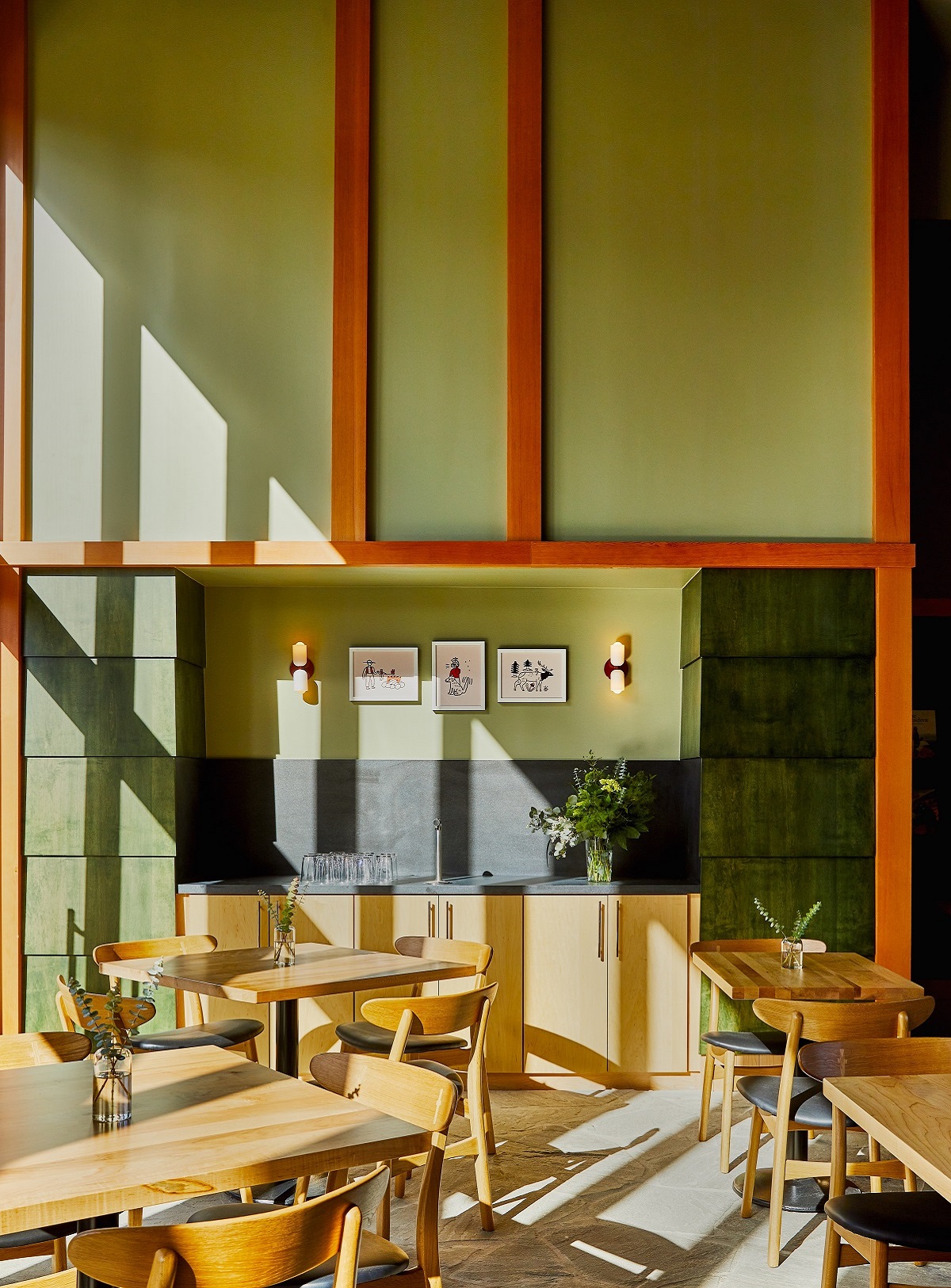 a corner of the restaurant with wooden tables and green tiled wall