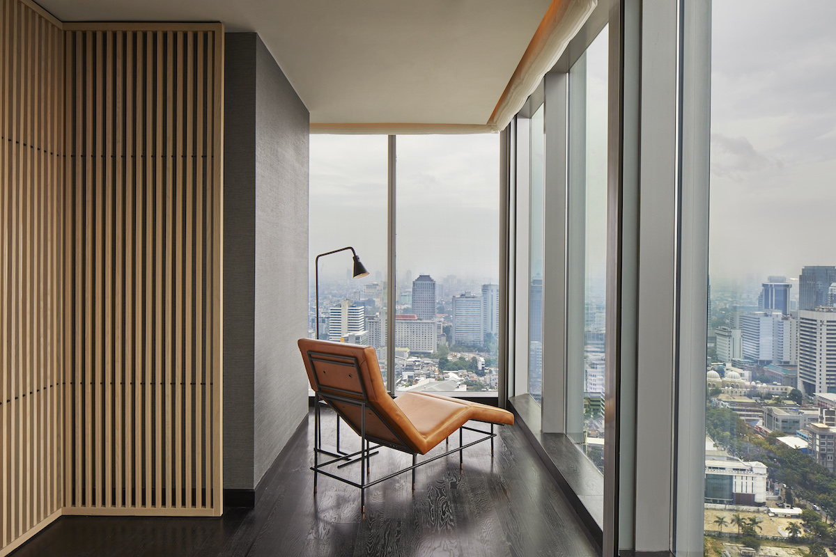 A lounge chair by the window in hotel overlooking Jakarta