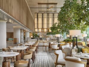 double volume dining space with statement architectural lighting and trees for indoor planting