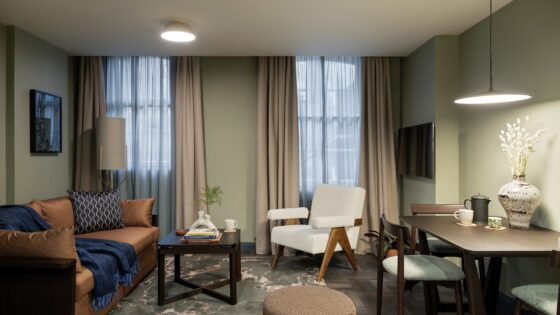 brown leather sofa with blue throw and grey and taupe walls and fabrics in Cove Kensington Apartment