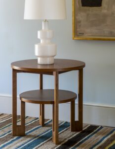 double tiered wooden side table on striped carpet with white geometric shaped lamp on the table