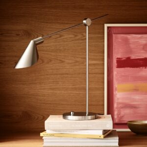 minimalist desk lap on a pile of books in front of a painting on a shelf