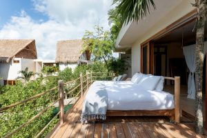 outdoor bed on wooden deck overlooking tree canopy at La Valise Tulum