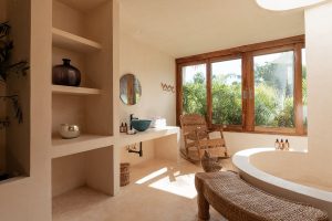 natural plaster, wood and rounded built bathtub in guestroom overlooking jungle trees in Tulum