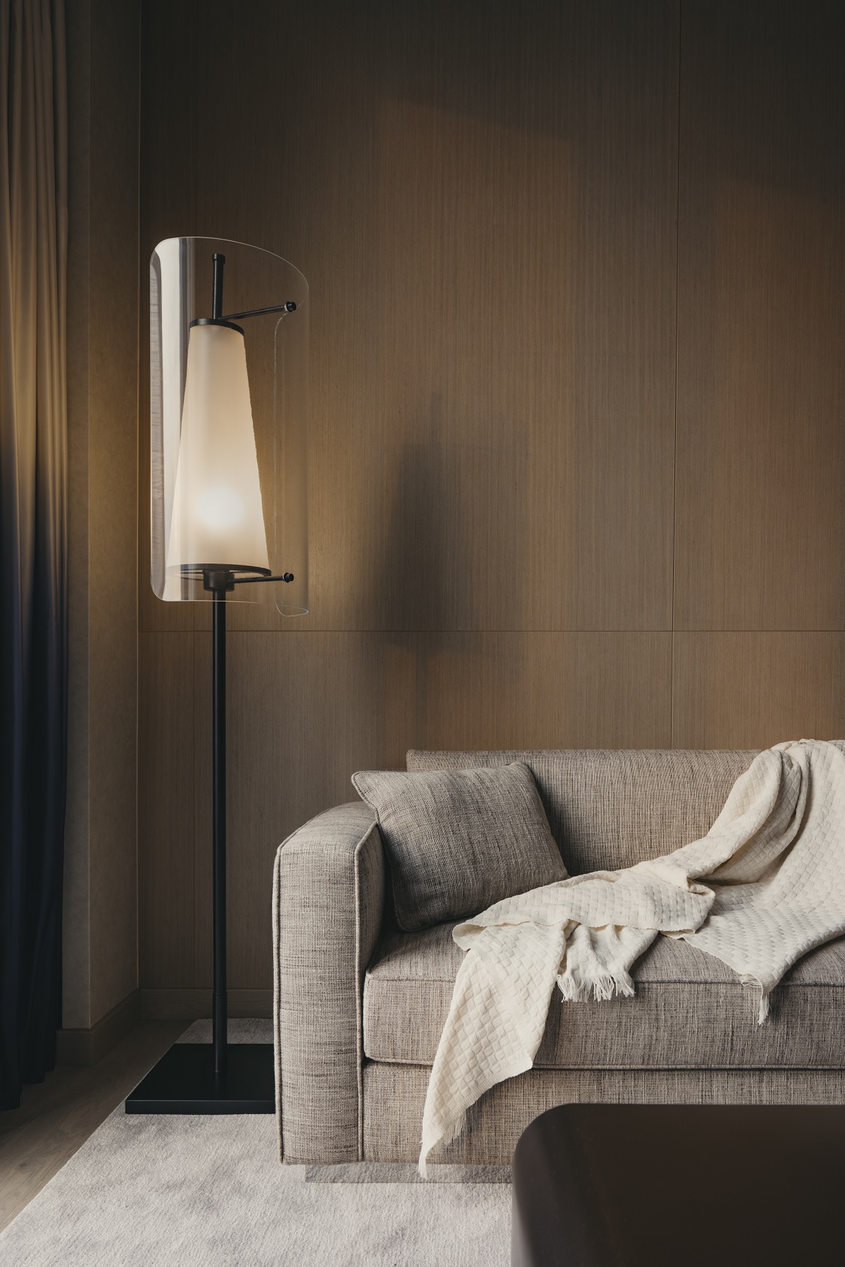 wood panelled walls and detail of soft cream couch with statement floor lamp in the Pinnacle Suite Mondrian Singapore