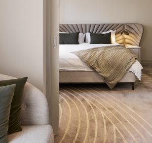 view through doorway to hotel guestroom with neutral colour scheme and art deco lines