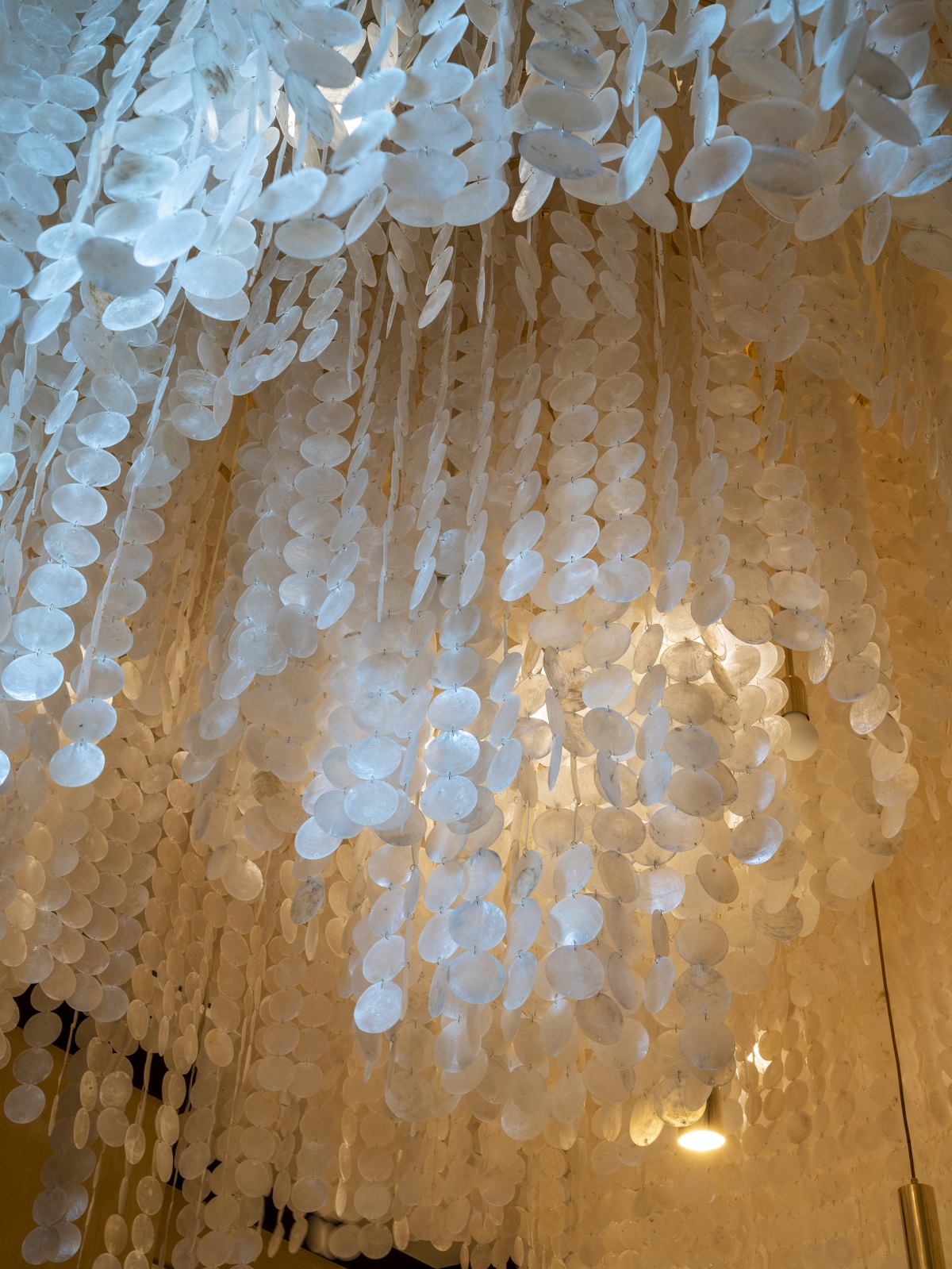 detail of dramatic mother of pearl bespoke ceiling light in Scarpetta private dining in the Waldorf Astoria Doha