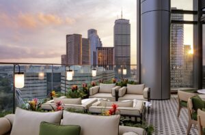 comfortable seating in wood and cream with lighting attached to a glass barrier on the roof terrace with views across Boston