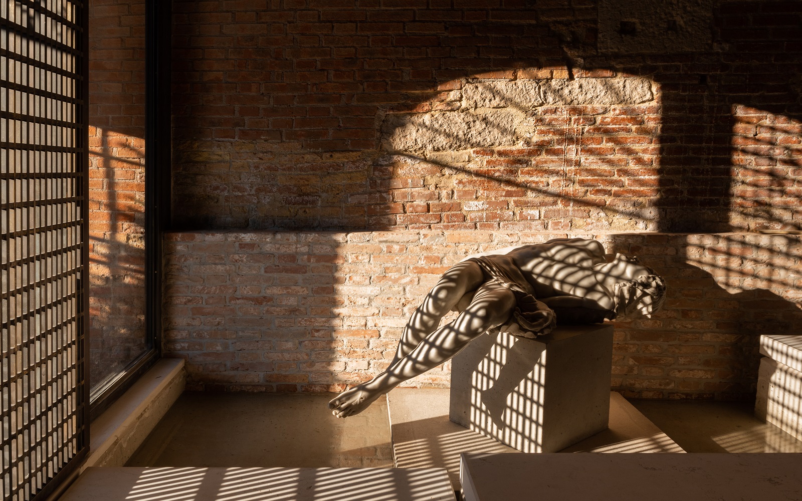 sunlight through window of Venice Venice hotel onto brick wall and reclining statue