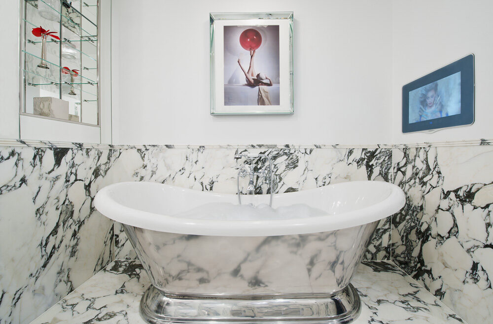 A luxury, freestanding bath with half marble stone wall surface covered