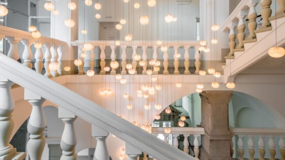 interior hallway and stairway of Wilmina hotel in white and cream with statement hanging lights in the centre